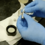 Compact tension fatigue crack growth specimen with crack mouth gauge attached for ASTM E647 test