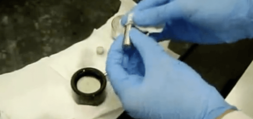 Compact tension fatigue crack growth specimen with crack mouth gauge attached for ASTM E647 test