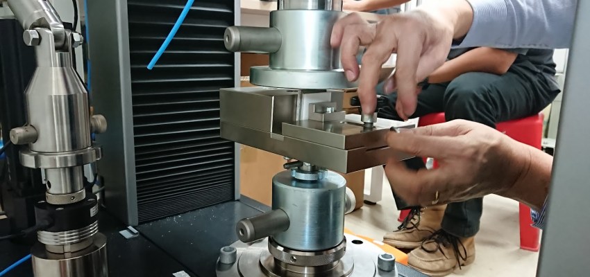 Steel specimen loaded into universal testing machine for mechanical tensile testing