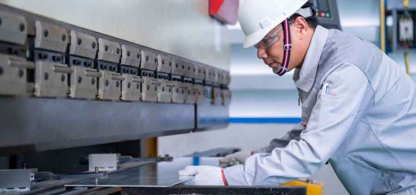 Metal dog-bone specimen loaded into tensile testing machine showing elongation
